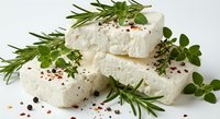 Fresh white cheese blocks with aromatic herbs and spices on clean background. Creamy dairy product garnished with rosemary, oregano and peppercorns for culinary use.