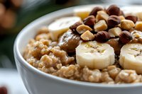 Healthy breakfast bowl with oatmeal, sliced bananas, chocolate chips, and peanut butter drizzle, photographed in natural light with selective focus.