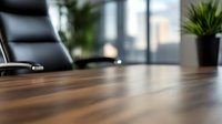 Empty modern conference room with wooden table and black leather chair, selective focus on polished surface, blurred office background with window and plant.