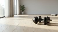 Pair of black dumbbells on light wooden floor in bright minimalist room with large windows and potted plant, fitness and gym equipment.