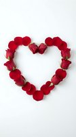 Red rose petals and buds arranged in heart shape on white background for Valentine's Day romance love wedding anniversary greeting cards.