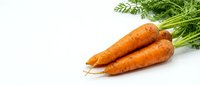 Fresh organic carrots with green tops isolated on white background for healthy cooking and nutrition concepts.