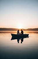 Romantic couple silhouettes sitting in boat on calm lake at golden sunrise with peaceful water reflections and serene morning atmosphere.