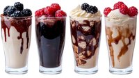Four gourmet milkshakes with chocolate and caramel drizzle topped with fresh berries and whipped cream in tall glasses on white background.