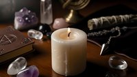 Mystical altar setup with burning candle, crystals, tarot cards and spiritual tools for meditation, witchcraft rituals and esoteric practices.