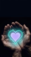 Cupped hands protecting glowing heart symbol with turquoise and purple gradient light against dark background representing love, care, protection and compassion.