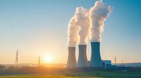 Nuclear power plant cooling towers emitting steam against golden sunrise sky, industrial energy production facility with transmission towers in background.