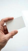 Close-up of a hand holding a blank white business card against a neutral background. Isolated on white for branding, corporate identity, and marketing mockup designs.