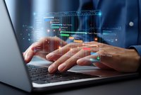 Businessman hands typing on laptop with holographic programming code interface displaying software development and digital technology innovation.