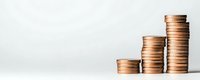 Growing stacks of bronze coins showing financial growth and investment progress on light neutral background, minimalist composition for business concepts.