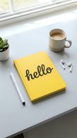 Yellow hello notebook on white desk with coffee cup, pen, wireless earbuds and succulent plant, bright minimal workspace flat lay.