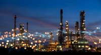 Industrial oil refinery complex illuminated at night with glowing lights against deep blue twilight sky for energy and manufacturing concepts.