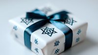 White gift box decorated with star pattern and dark teal ribbon bow against light background, festive holiday present wrapping for special occasions.