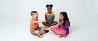 Three diverse children sitting cross-legged on white background sharing stories and laughing together in colorful casual clothing for education content.