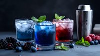 Vibrant cocktails in blue and red hues garnished with fresh berries and mint leaves on dark background, served with ice cubes and cocktail shaker.