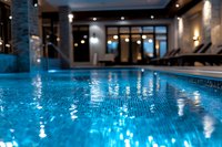 Luxurious indoor swimming pool with turquoise water reflecting ambient lighting, mosaic tiles, and modern spa interior design elements creating serene atmosphere.