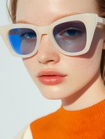Young Caucasian woman wearing stylish white sunglasses with gradient lenses and bright orange sweater in natural sunlight for fashion and lifestyle content.