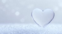 Pure white heart shape on sparkling snow surface with soft bokeh background, winter romance concept for Valentine's Day cards and romantic designs.