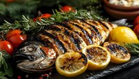 Grilled whole fish with lemon slices and herbs on dark slate, perfect for restaurant menus, cooking blogs, and culinary marketing materials.