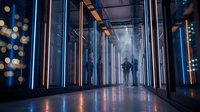 Futuristic data center corridor with glowing server racks and silhouetted technician figure walking through modern technology infrastructure facility.
