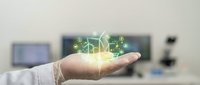 Businessman hand holding glowing green renewable energy icons with wind turbines and solar panels representing sustainable technology solutions.