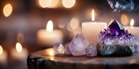 Amethyst crystals and clear quartz stones arranged with glowing candles creating peaceful meditation atmosphere for spiritual healing and wellness practices.