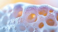 Abstract cellular foam structure with organic holes and bubbles in soft pastel colors for scientific and medical design applications.