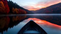 Wooden boat on tranquil lake at sunset, surrounded by autumn forest with red and orange foliage reflecting in mirror-like water surface against dramatic sky.