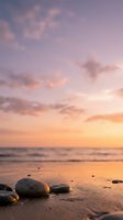 Smooth stones rest on sandy shore at sunset with golden light reflecting on calm ocean waves and soft clouds above.