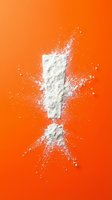 White flour powder explosion splash on vibrant orange background creating dynamic culinary motion effect for cooking and baking concepts.