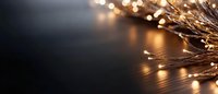 Glowing golden fairy lights creating magical bokeh effect against dark background, soft focus decorative illumination for festive mood and celebrations.