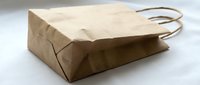 Brown kraft paper shopping bag with handles on white background isolated for retail packaging and eco-friendly commercial use in sustainable business.