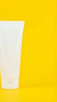 White cosmetic tube with pump dispenser on bright yellow background, isolated for skincare, beauty product packaging, and cosmetics advertising design.