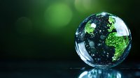 Crystal globe showing green continents on dark background with bokeh effect, representing environmental conservation and global sustainability concept.