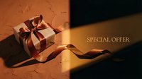 Elegant gift box with golden ribbon on textured surface, dramatic light and shadow, special offer text for luxury holiday promotion.