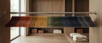 Modern walk-in closet with organized colorful clothing on hangers, wooden shelving and minimalist interior design for home organization and storage.