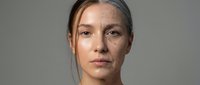 Middle-aged Caucasian woman with natural aging skin and gray hair showing confidence and authenticity in professional portrait for skincare campaigns.