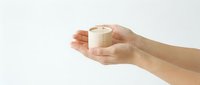Female hands gently holding white lit candle against clean white background for meditation, spa treatments, aromatherapy and relaxation concepts.
