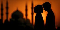Romantic couple silhouette against mosque backdrop at sunset, intimate moment with Islamic architecture, love and spirituality concept for wedding designs.