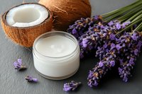 Natural cosmetic cream with fresh coconut and lavender flowers on dark stone background, organic skincare and spa concept for beauty products.