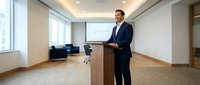 Professional businessman presenting at wooden podium in modern conference room with projection screen and city view windows.
