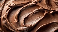 Creamy chocolate frosting texture with smooth swirls and waves creating rich, indulgent patterns. Close-up macro shot showing glossy surface and velvety consistency.