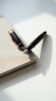 Elegant black fountain pen and ballpoint pen resting on open notebook with blank pages, professional writing instruments for business correspondence and journaling.