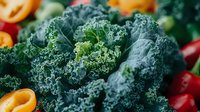 Fresh curly kale leaves with vibrant green texture close up, surrounded by colorful cherry tomatoes and kumquats creating healthy food composition.