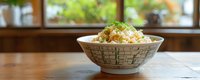 Fresh homemade coleslaw salad with cabbage and carrots in ceramic bowl on wooden table near bright window for healthy eating and cooking concepts.