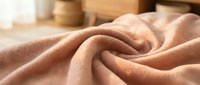 Soft pink fabric with gentle folds creating elegant textile waves, perfect for fashion design, home decor projects, and creative backgrounds.