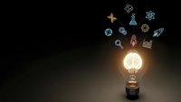 Glowing light bulb with colorful science and technology icons floating above on dark background representing innovation and creative ideas.
