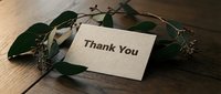 Thank you card on rustic wooden table with green eucalyptus branches, elegant gratitude note for weddings, events, and appreciation messages.