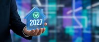 Businessman holding glowing house icon with checkmark and 2027 text, representing future property investment, real estate goals, and smart home technology solutions.
