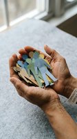 Hands holding colorful paper cutout figures representing community, teamwork, diversity and social connection in warm natural light for unity concepts.